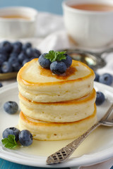 A stack of scotch pancakes with with honey and blueberries
