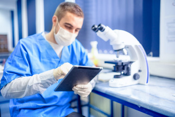 chemist working with tablet and microscope in laboratory