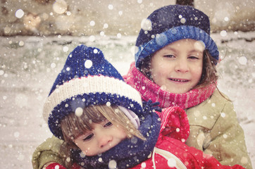 Two little sisters having fun on white and snowy winter day