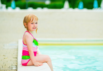 Portrait of baby girl sitting at poolside