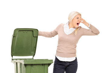 Woman opening a stinky trash can