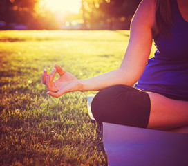  hands of a woman meditating in a yoga pose on the grass toned w