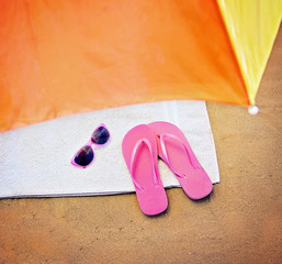the top of an umbrella and pink flip flop sandals and sunglasses