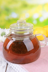 Teapot with tea on table on bright background