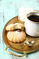Cup of coffee with tasty cookie on color wooden background