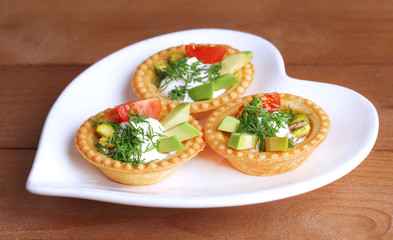Tartlets with greens and vegetables with sauce on plate on