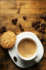 Cup of espresso and tasty cookie on wooden background