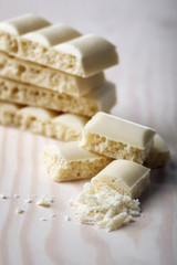 Tasty white porous chocolate on wooden table, close up