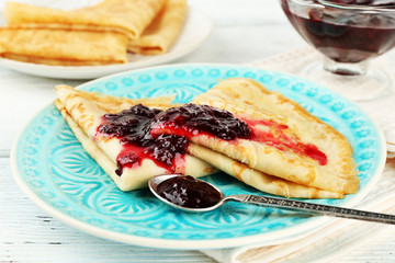 Plate of delicious pancakes with berry jam on wooden background