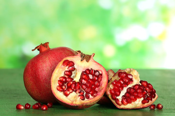 Juicy ripe pomegranates on green wooden table