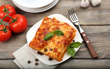 Portion of tasty lasagna on wooden table - obrazy, fototapety, plakaty
