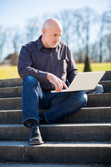 Obraz premium Man sitting on a bench using a laptop