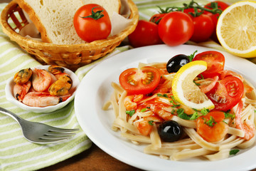 Tasty pasta with shrimps, mussels, black olives and tomato