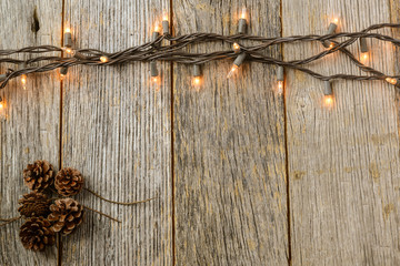 Christmas Lights and Pine cones on Rustic Wood Background