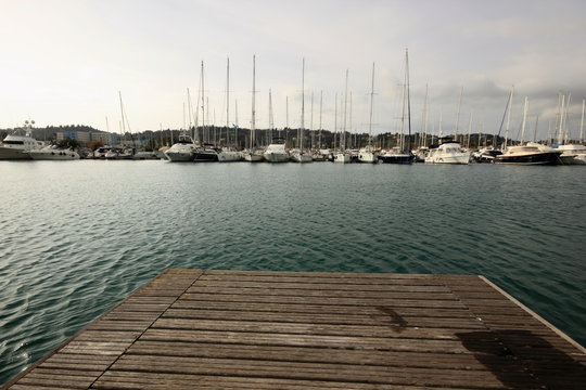 wood marina pontoon with sail boats and yachts