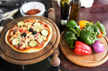 Cheese on a freshly prepared pizza on wooden board.