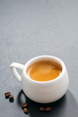 cup of espresso and coffee beans on a dark background, vertical