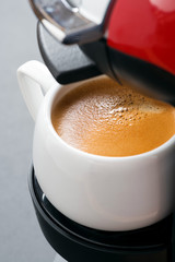 cup of espresso in the coffee machine close-up, vertical