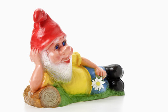 Gartenzwerg liegend mit Blume in der Hand