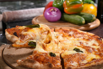 Close up of pizza and ingredients on wooden board.