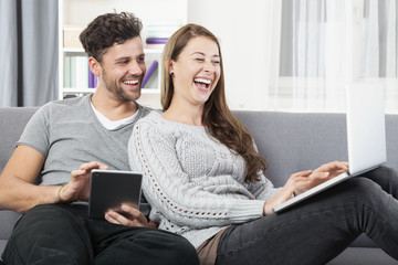 Junges glückliches Paar schaut lachend auf einen Laptop