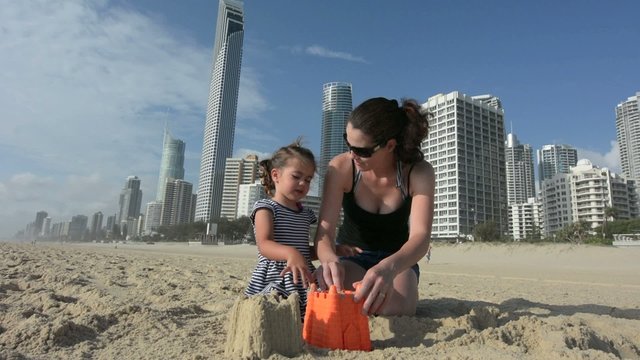 Mother and daughter builds sand castle