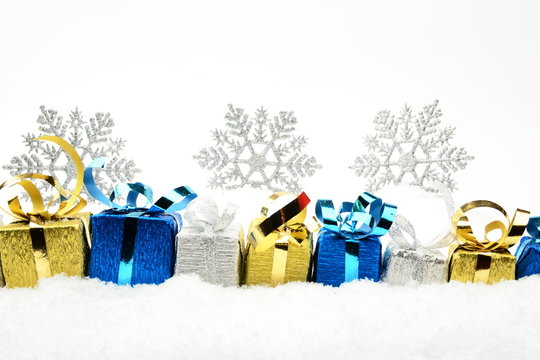 Silver,blue,golden christmas gifts with snowflakes on snow