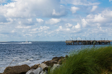 Obraz premium White Cabin Cruise Headed Past Pier and Rock Wall