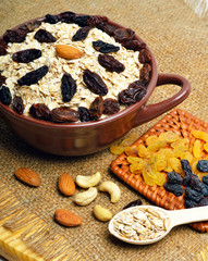 Oatmeal in ceramic plate, spoon, raisins, cashews and almonds on