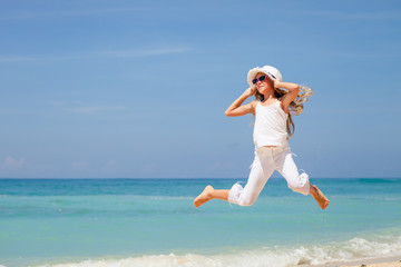 teen girl  jumping on the beach at blue sea shore in summer vaca