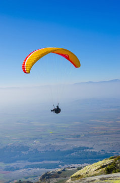 orange paraglider on the blue sky