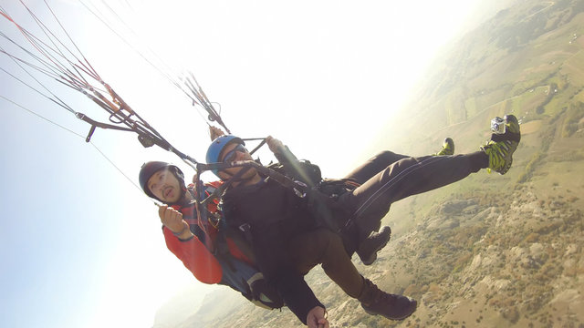 Tourist playing paragliding guided by a pilot