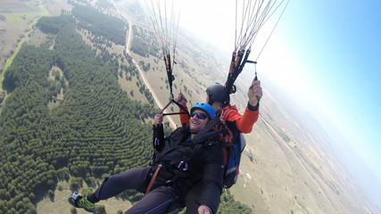 Tourist playing paragliding guided by a pilot