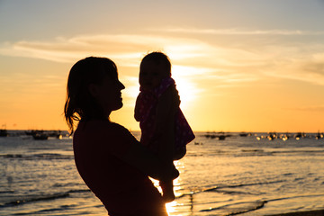 happy mother and baby having fun at sunset beach