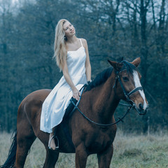 Obraz premium romantic sensual girl in white dress on a horse in the forest
