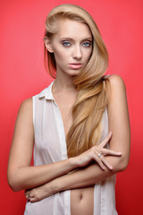 Beautiful seminude blonde woman at red background.