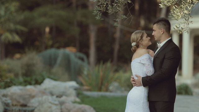 The groom in a suit hugging the bride in an elegant dress and