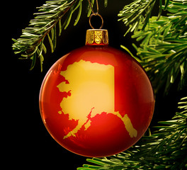 Red bauble with the golden shape of Alaska hanging on a christma