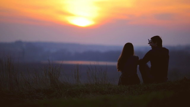 The pair, lovers, sit by sunset background on the top