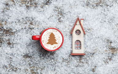 Cappuccino with christmas tree shape and toy home on artificial