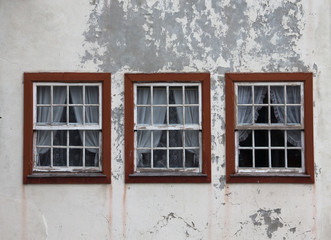 three windows on the shabby wall closed with curtains