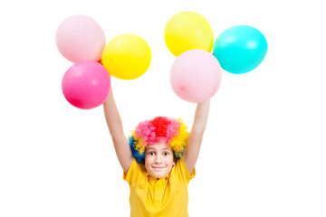 Fototapeta na wymiar Smile boy in clown wig hands up with balloons