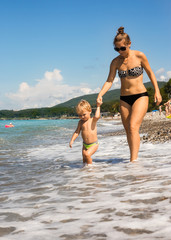 Fototapeta premium Mum with kid go near sea edge