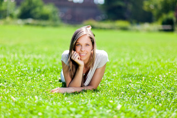 Young smiling woman lying down on the grass