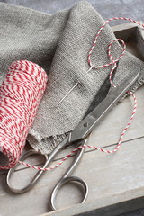 Scissors, spool of thread, needle and sackcloth on wooden tray