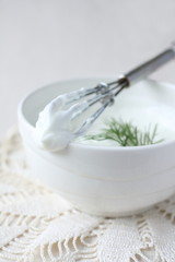 Fresh cream cheese spread in white bowl with dill and corolla