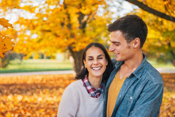 Obraz premium Portrait of smiling young couple outdoors in park in autumn