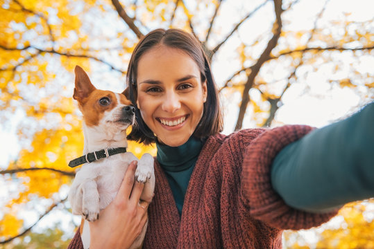 Portrait of smiling young woman with dog outdoors in autumn