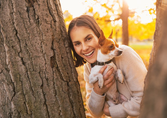 Happy young woman with dog outdoors in autumn park