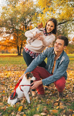 Naklejka na ściany i meble Young couple with dogs pointing on copy space outdoors in autumn